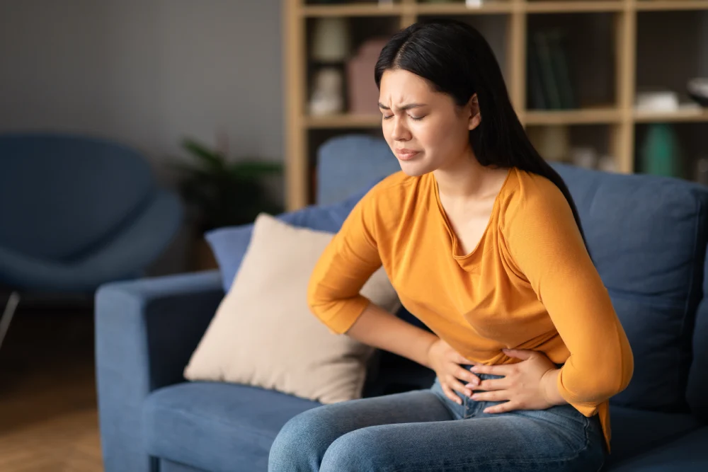 Female patient experiencing fibroid-related pain, considering treatment at a gynae clinic in Singapore